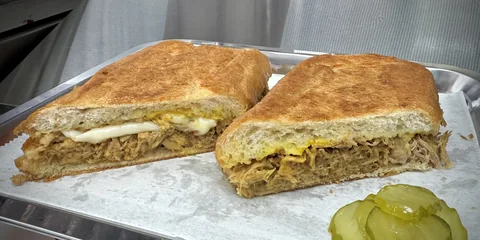 Pan con Lechón sandwich cut in half, showing the roasted pork filling
