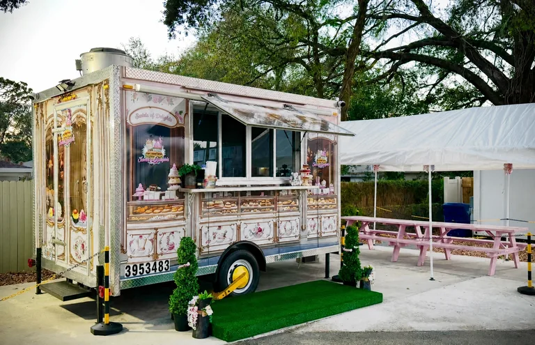 Swirls of Delights food truck beside pink picnic tables under a white canopy